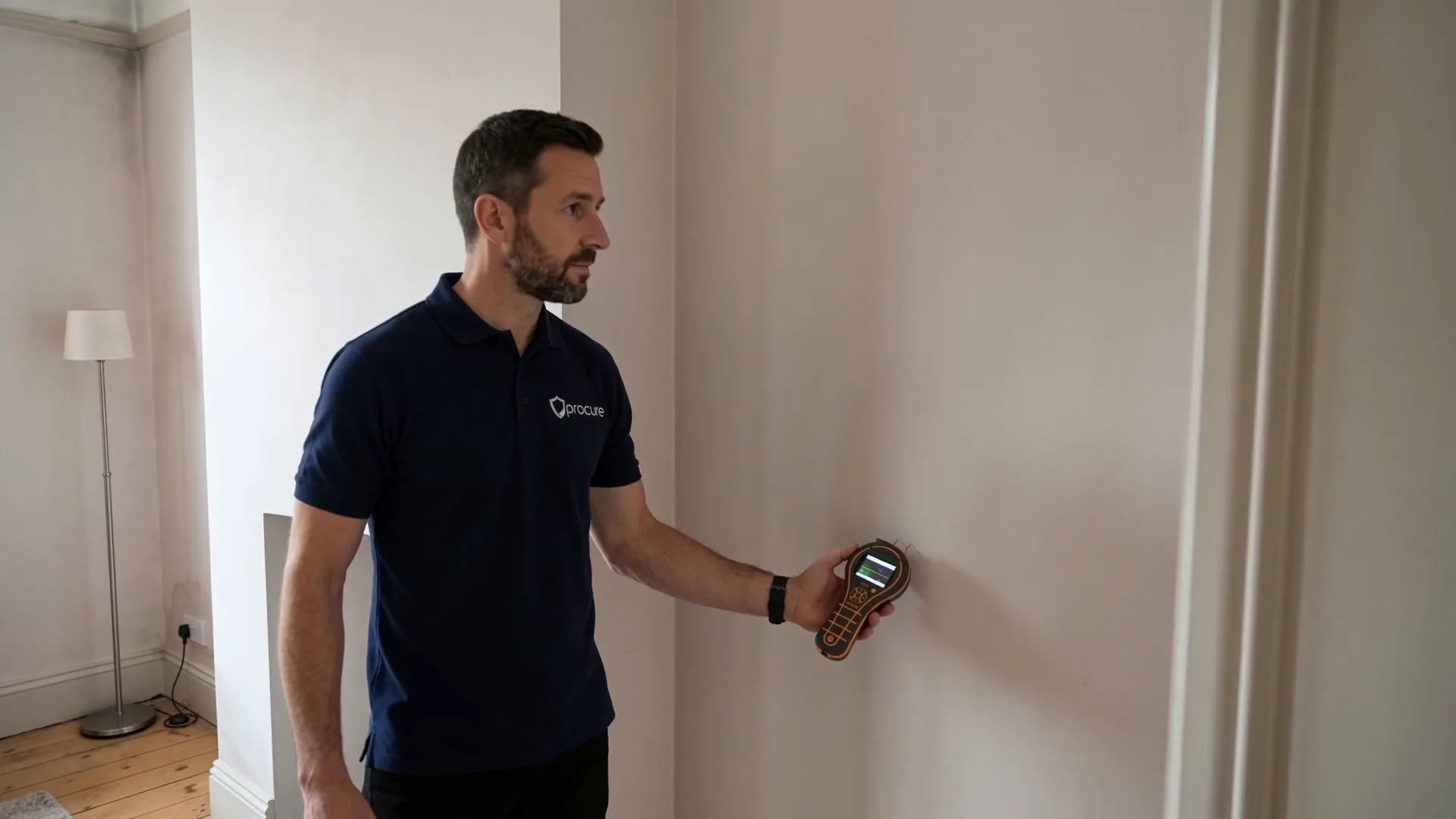 A Procure Group damp surveyor taking a moisture reading from a wall with a hand-held meter