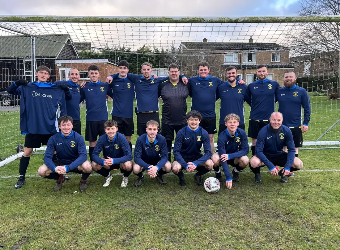 The local football team Procure Group sponsors, lined up in front of the goal holding a Procure-branded shirt